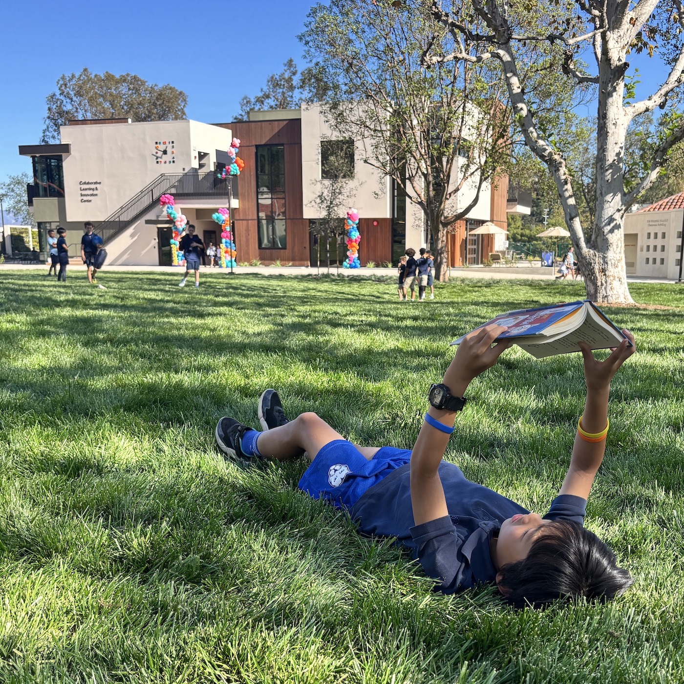 View of Curtis School CLIC from campus quad. A student reads a book on the lawn of the Collaborative Learning and Innovation Center, a Los Angeles educational architectural project by Pica + Sullivan Architects.
