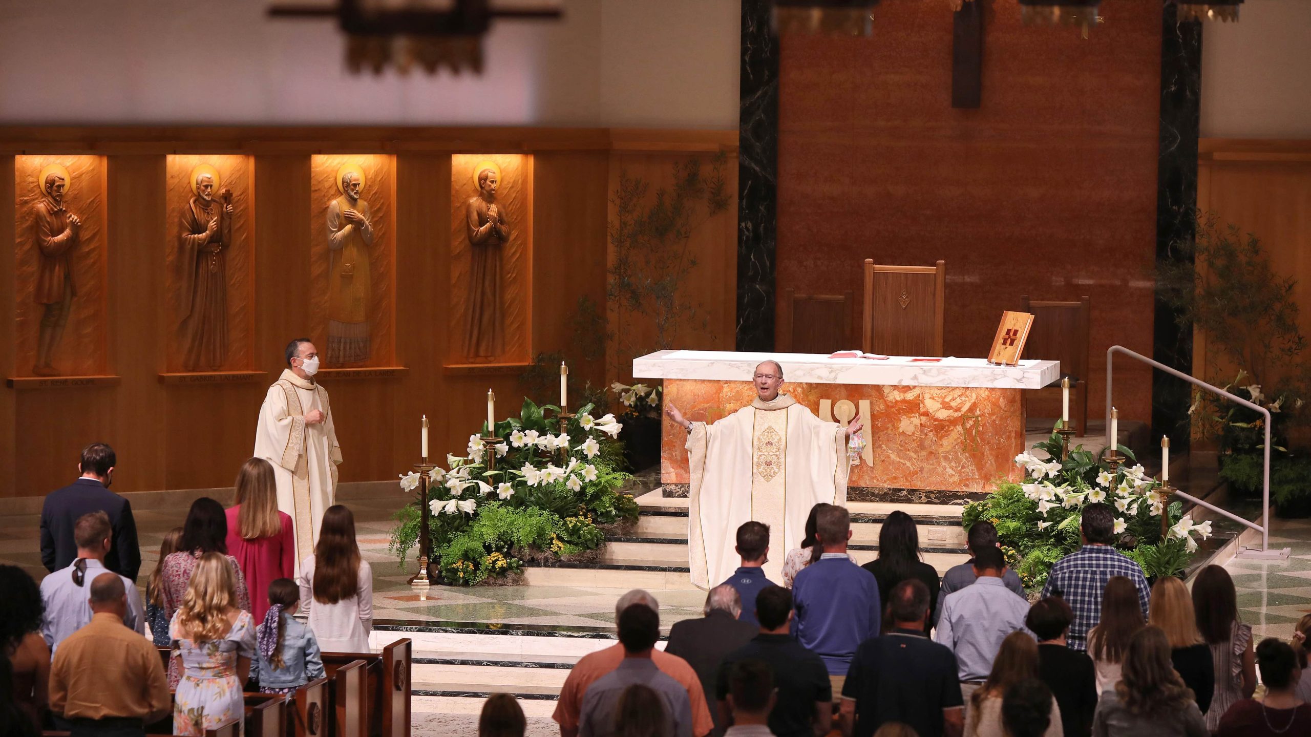A priest performing a service at the altar at the American Martyrs Church, a Southern California Religious Architecture Project by Pica + Sullivan Architects.