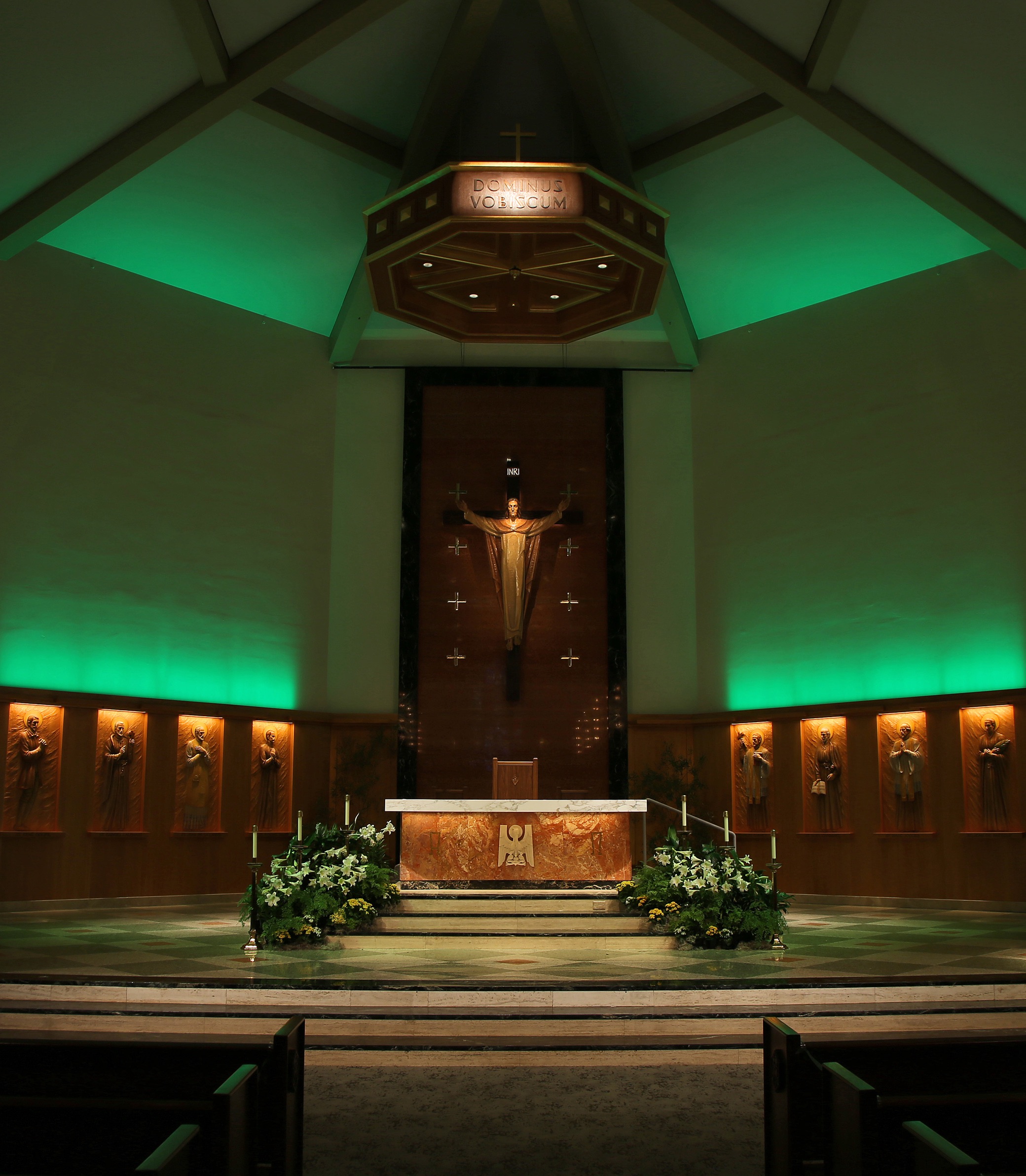 A medium front-on shot of the altar with green lighting in the American Martyrs Church, a Southern California Religious Architecture Project by Pica + Sullivan Architects.