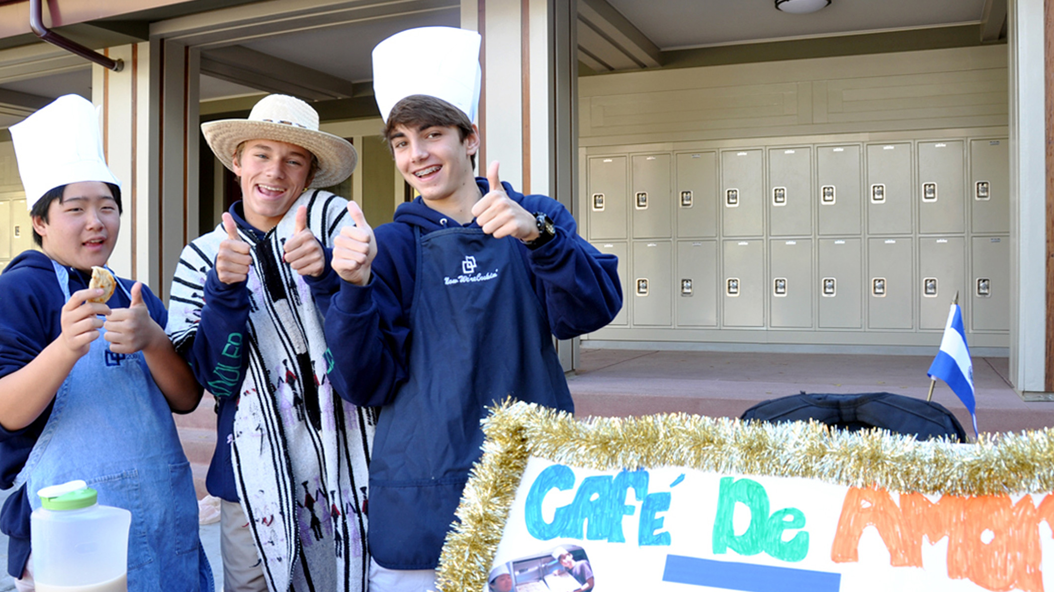 Three students in costume give thumbs-up to the camera in front of an outdoor bank of lockers at the Chandler School in Pasadena, an educational architecture project in Southern California.