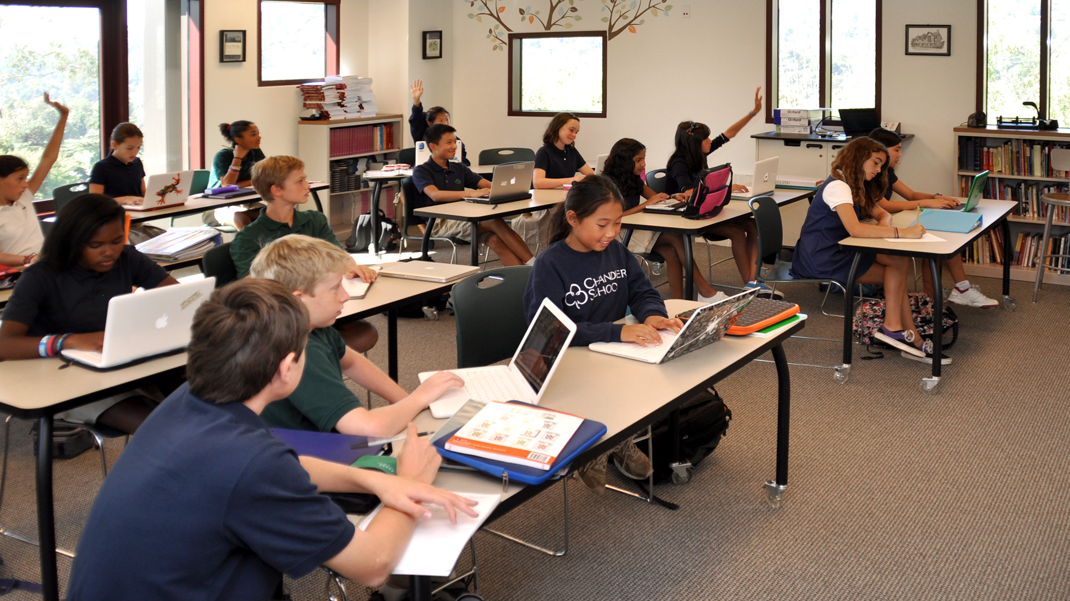 Students raise their hands and work on their laptops in a classroom at the Chandler School in Pasadena, an educational architecture project in Southern California.