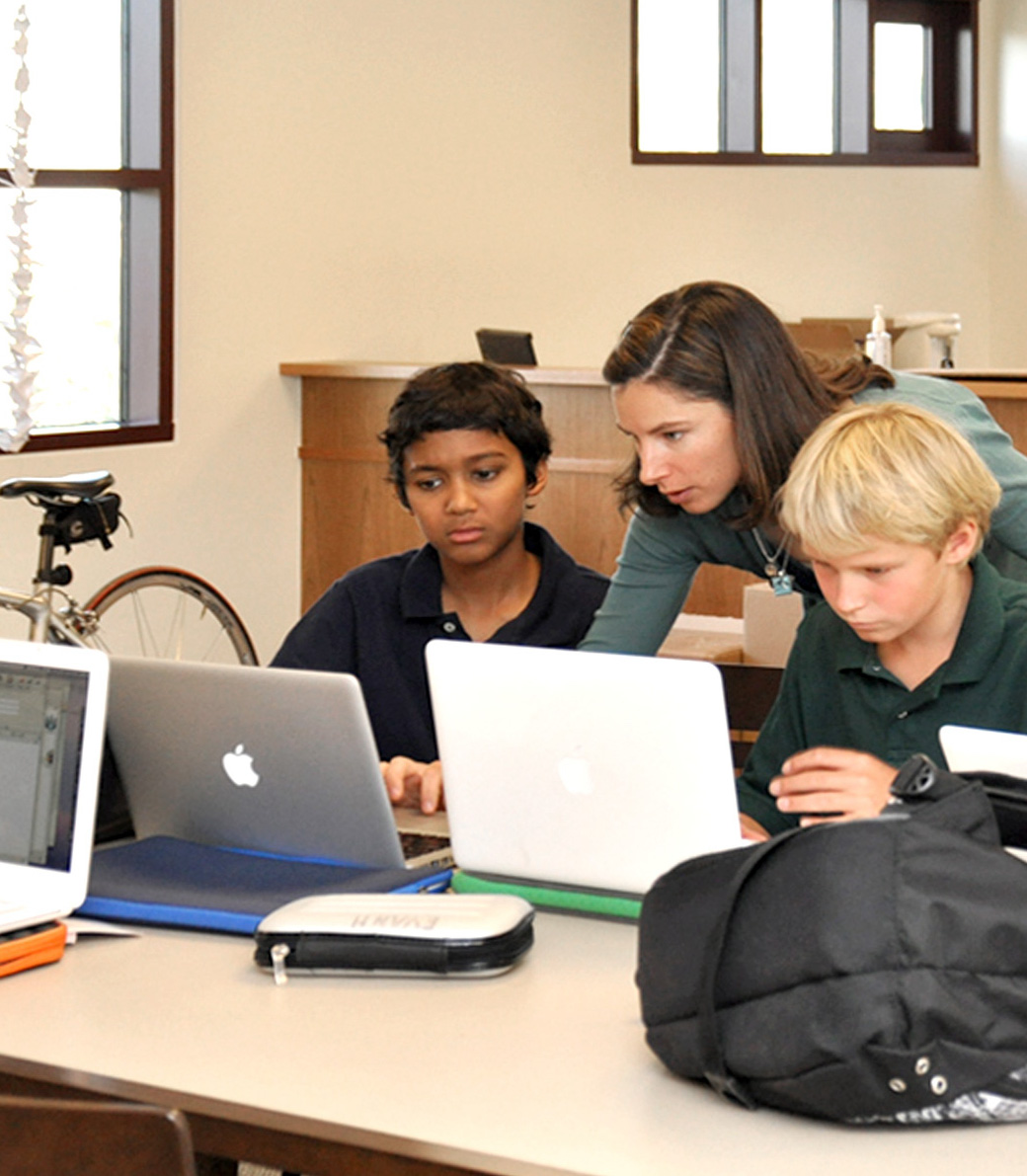 A teacher helps two students with work on their laptops in a classroom at the new middle school at the Chandler School in Pasadena, an educational architecture project in Southern California.