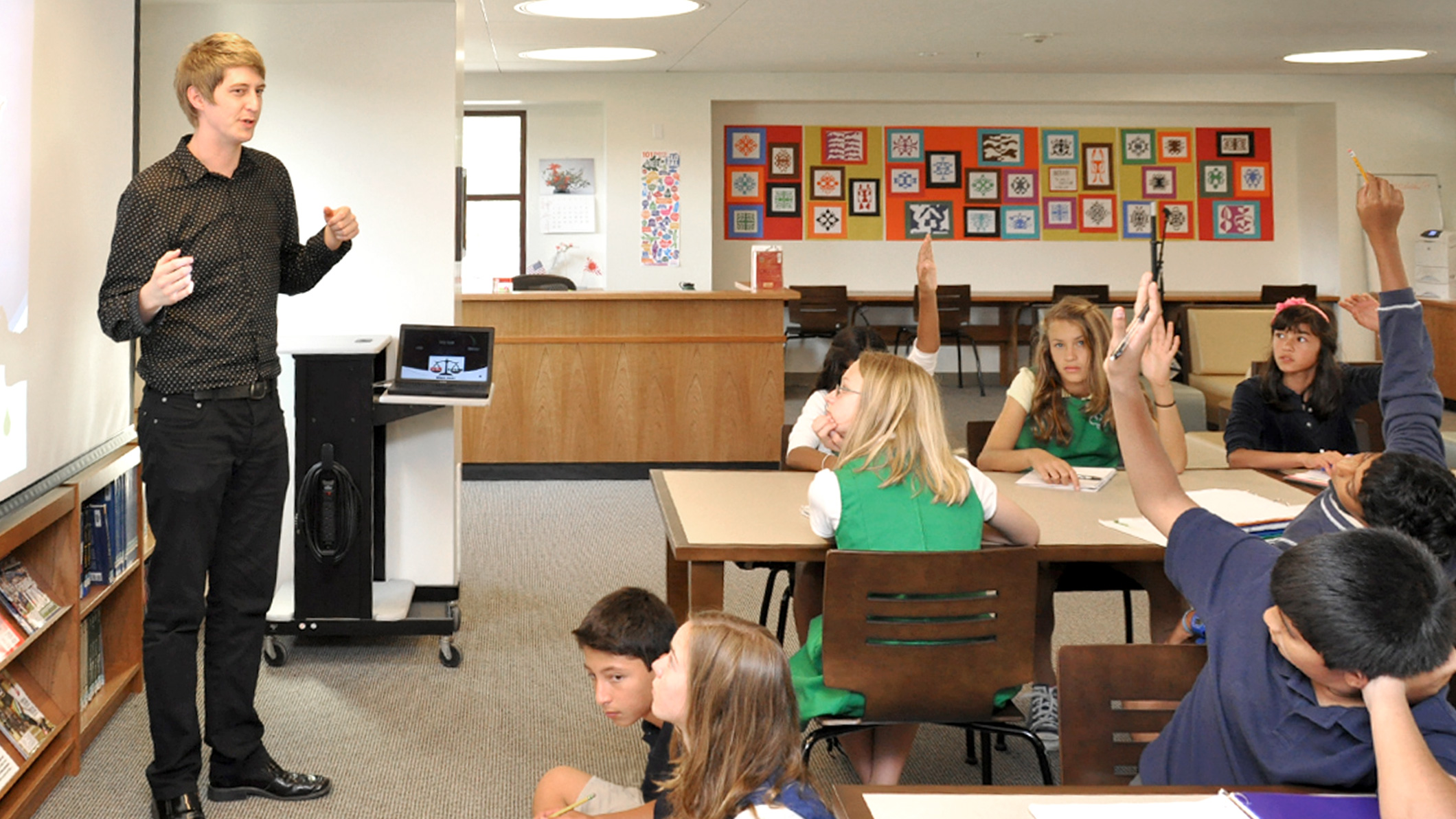 Students raise their hands to answer a teacher in a classroom the Chandler School in Pasadena, an educational architecture project in Southern California.