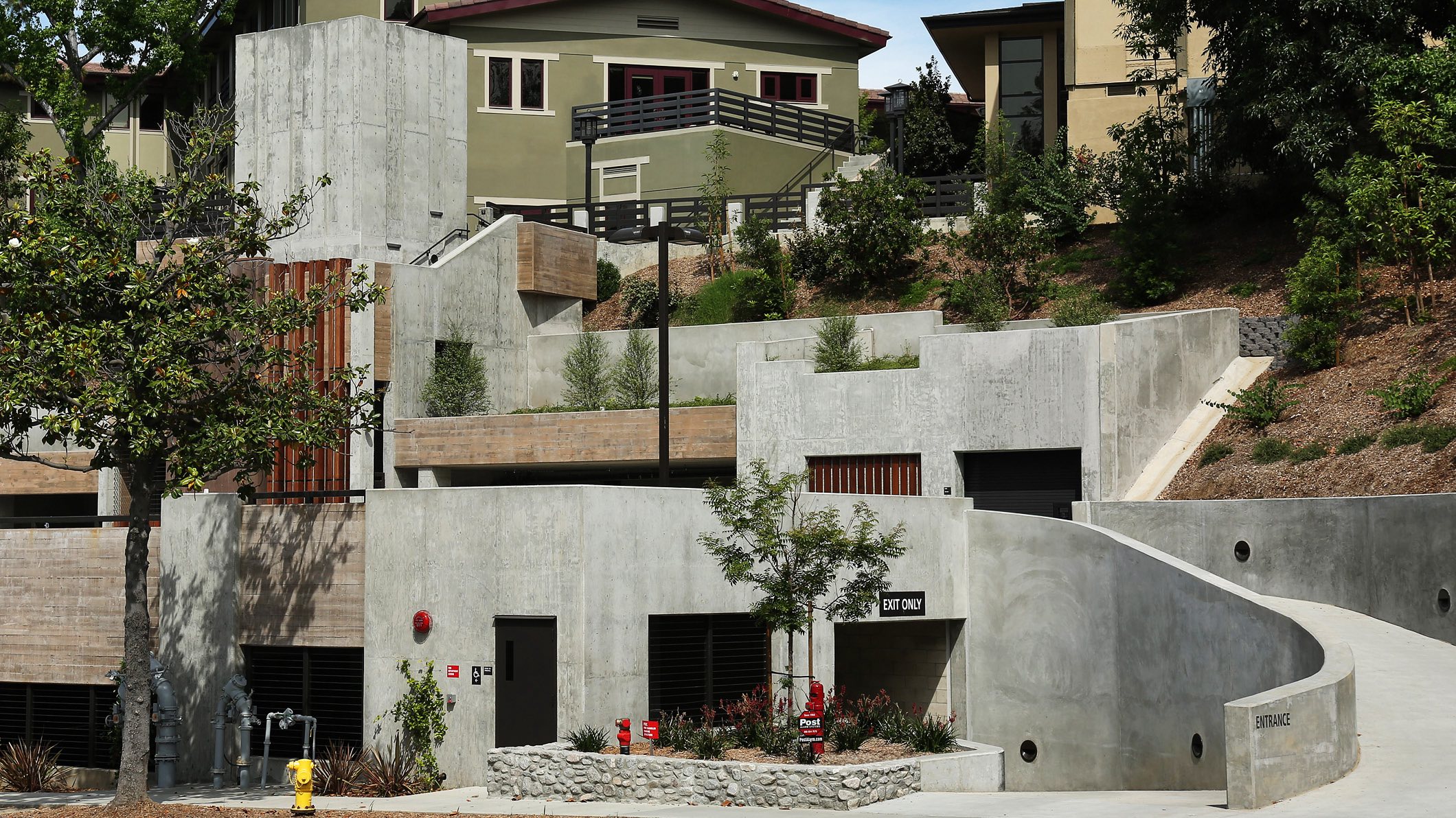 Roadside view of the new, multi-level parking structure at Chandler School in Pasadena, the buildings of the school visible on the hill behind the parking structure.
