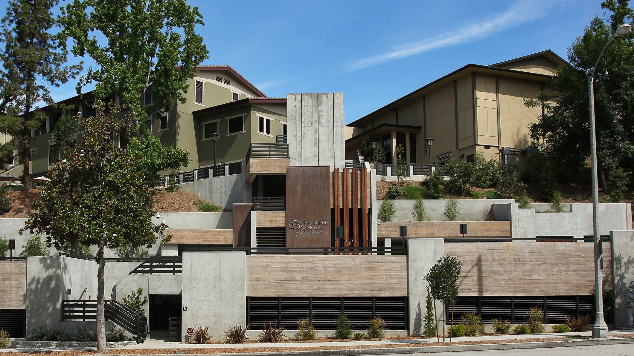 Exterior view of the multi-level new parking structure at Chandler School in Pasadena. School buildings are visible on the hill behind it.