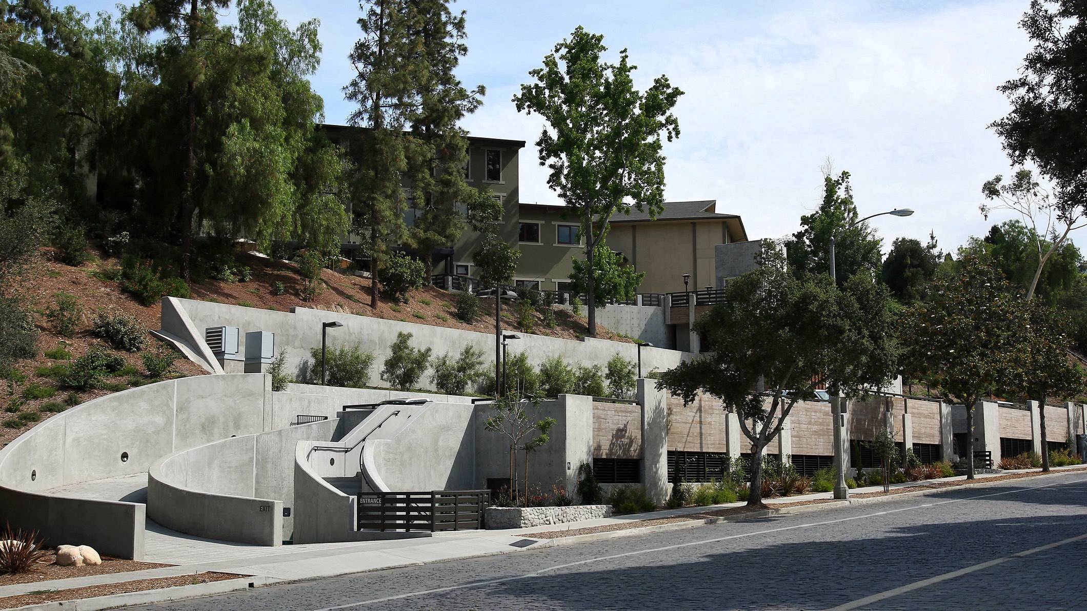 View of the new parking structure at Chandler School in Pasadena from the street, the buildings of the school visible on the hill behind the parking structure.