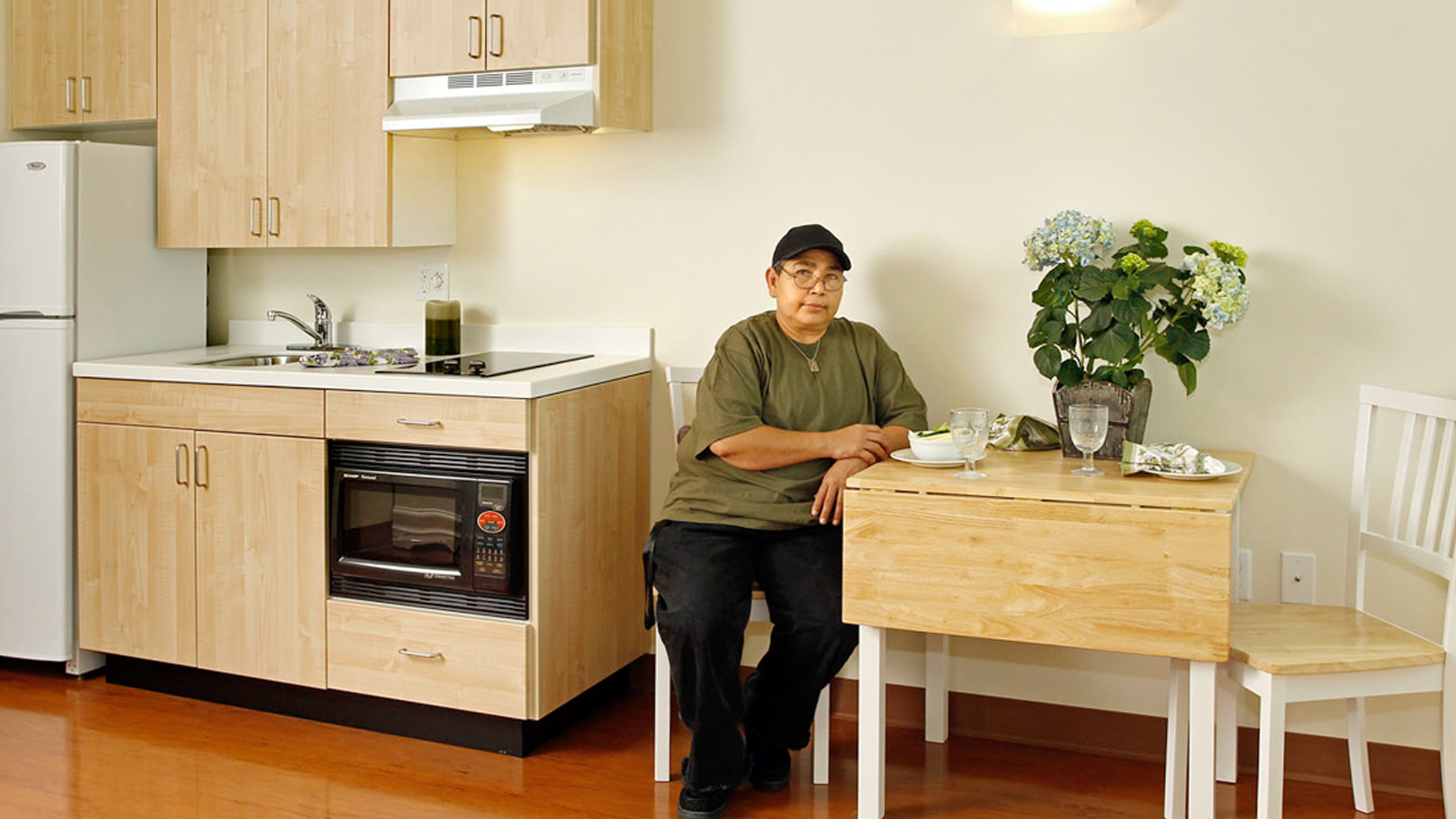 A woman eats in a small kitchen at Downtown Women's Center in Los Angeles, a Pica+Sullivan Southern California non-profit architectural renovation project.
