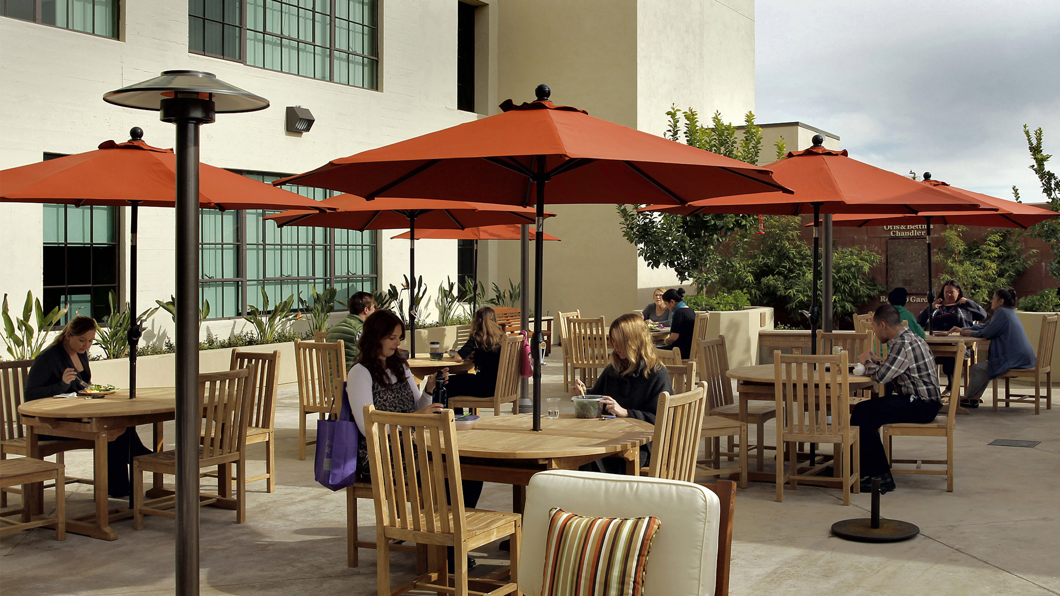 People sit and eat at tables in the rooftop garden at the Downtown Women's Center in Los Angeles, a Pica+Sullivan Southern California non-profit architectural renovation project.