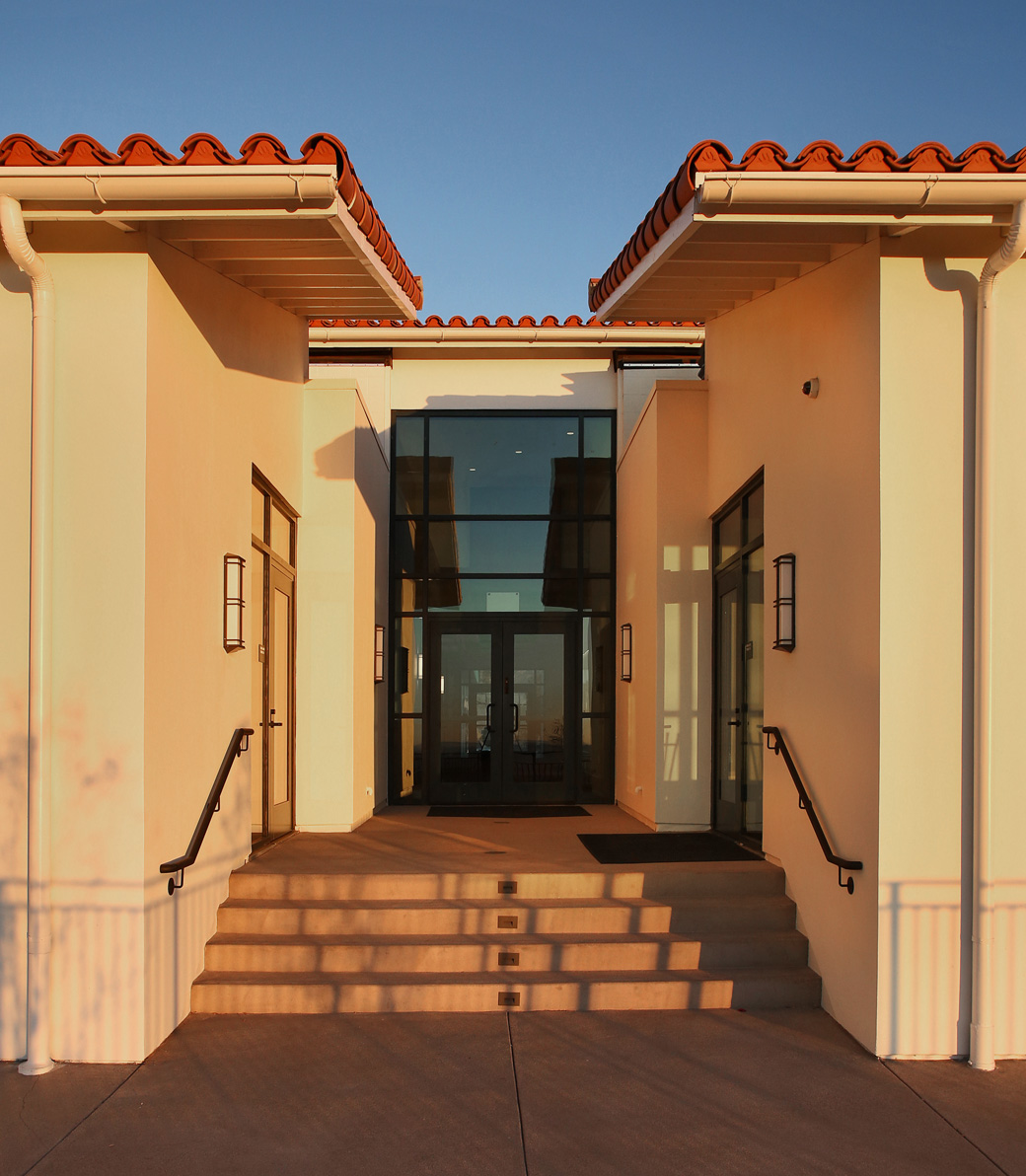 Expanded Mozilo Family Center for the Arts – Pica + Sullivan.com Sunset at a small exterior staircase entrance to the Mozilo Family Center for the Arts at the Flintridge Sacred Arts Academy, an educational architectural project in Southern California. The door faces the camera, the interior faintly visible through the glass.
