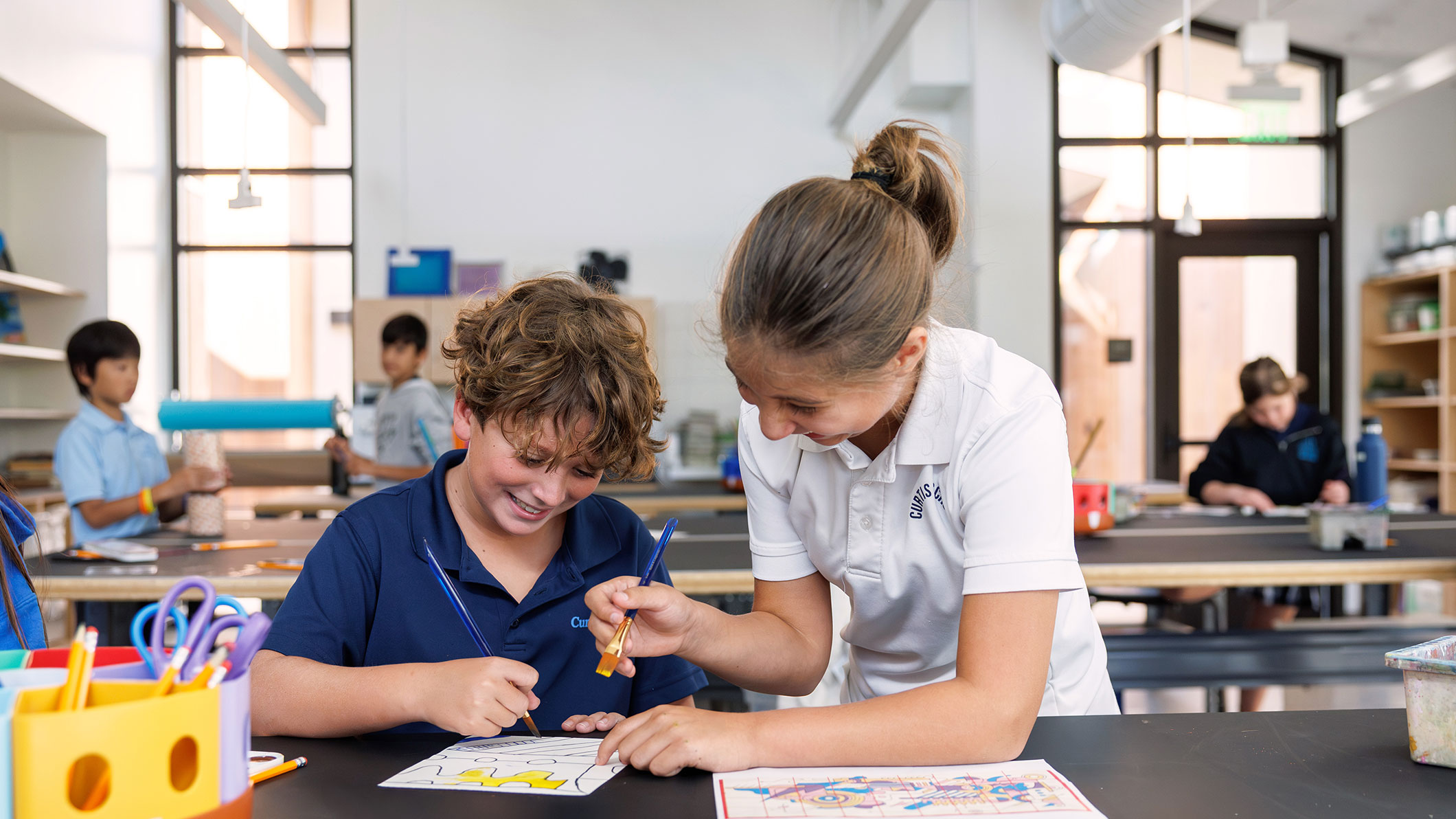 Two students painting in a classroom at the Collaborative Learning and Innovation Center, a Los Angeles educational architectural project by Pica + Sullivan Architects.