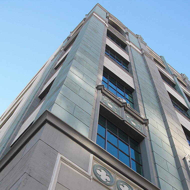Exterior of the Downtown Women's Center in Los Angeles, a Pica+Sullivan Southern California non-profit architectural renovation project, from a low angle, focusing on the windows and decorative features.