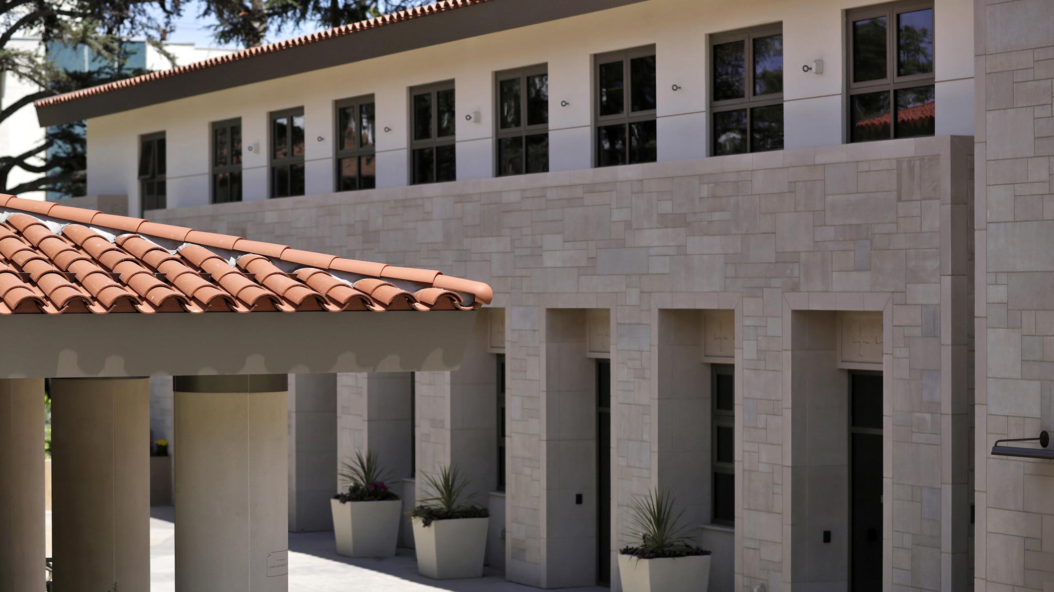 Exterior of the Saint Monica Community Center in Santa Monica, a Pica+Sullivan Southern California educational and religious architectural project, showcasing the design work, second-floor windows, and rooftops.