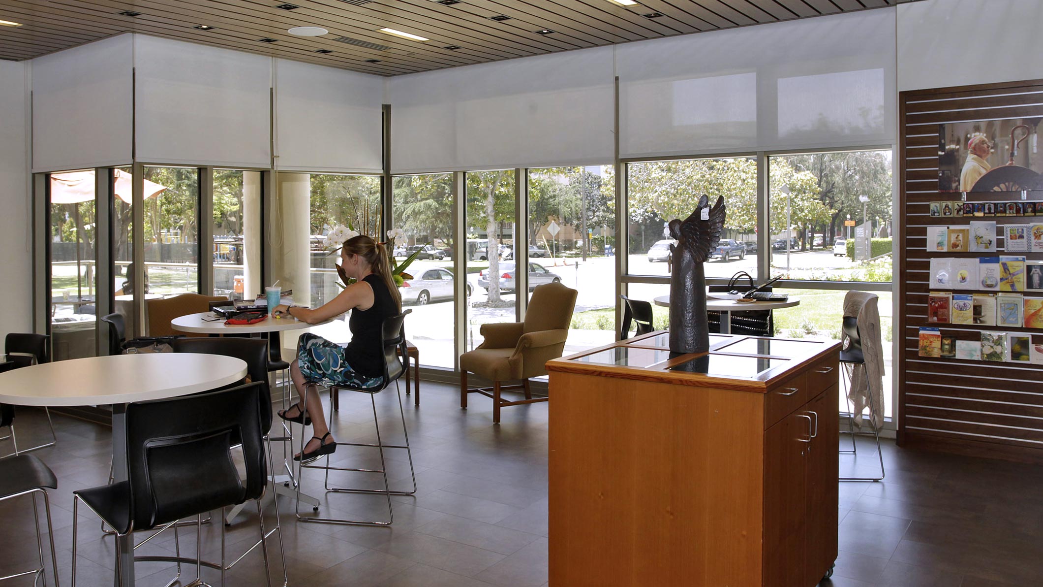 A woman sits at a table in a coffee and community room at the Saint Monica Community Center in Santa Monica, a Southern California religious architectural project.