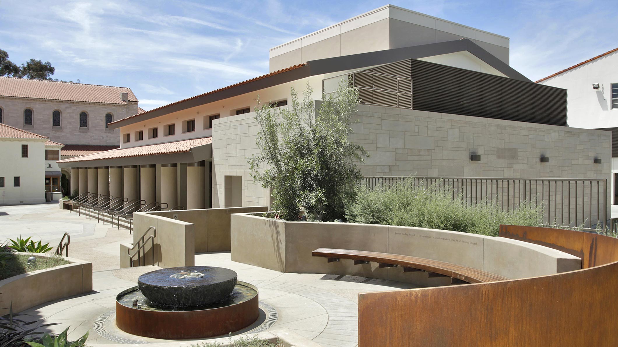 Exterior of a plaza area with benches and a fountain at the Saint Monica Community Center in Santa Monica, a Pica+Sullivan Southern California educational and religious architectural project.