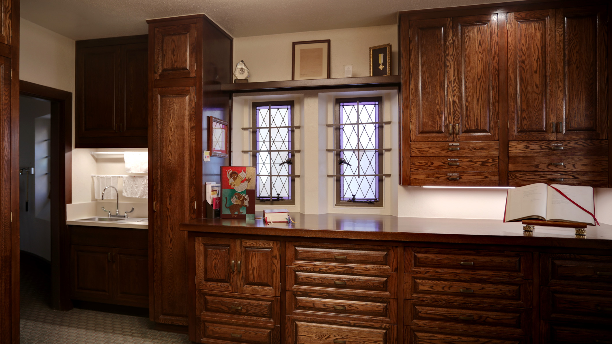 A room with wood cabinets and a sink and towels the Saint Monica Church in Santa Monica, a Pica+Sullivan Southern California religious architectural renovation project.