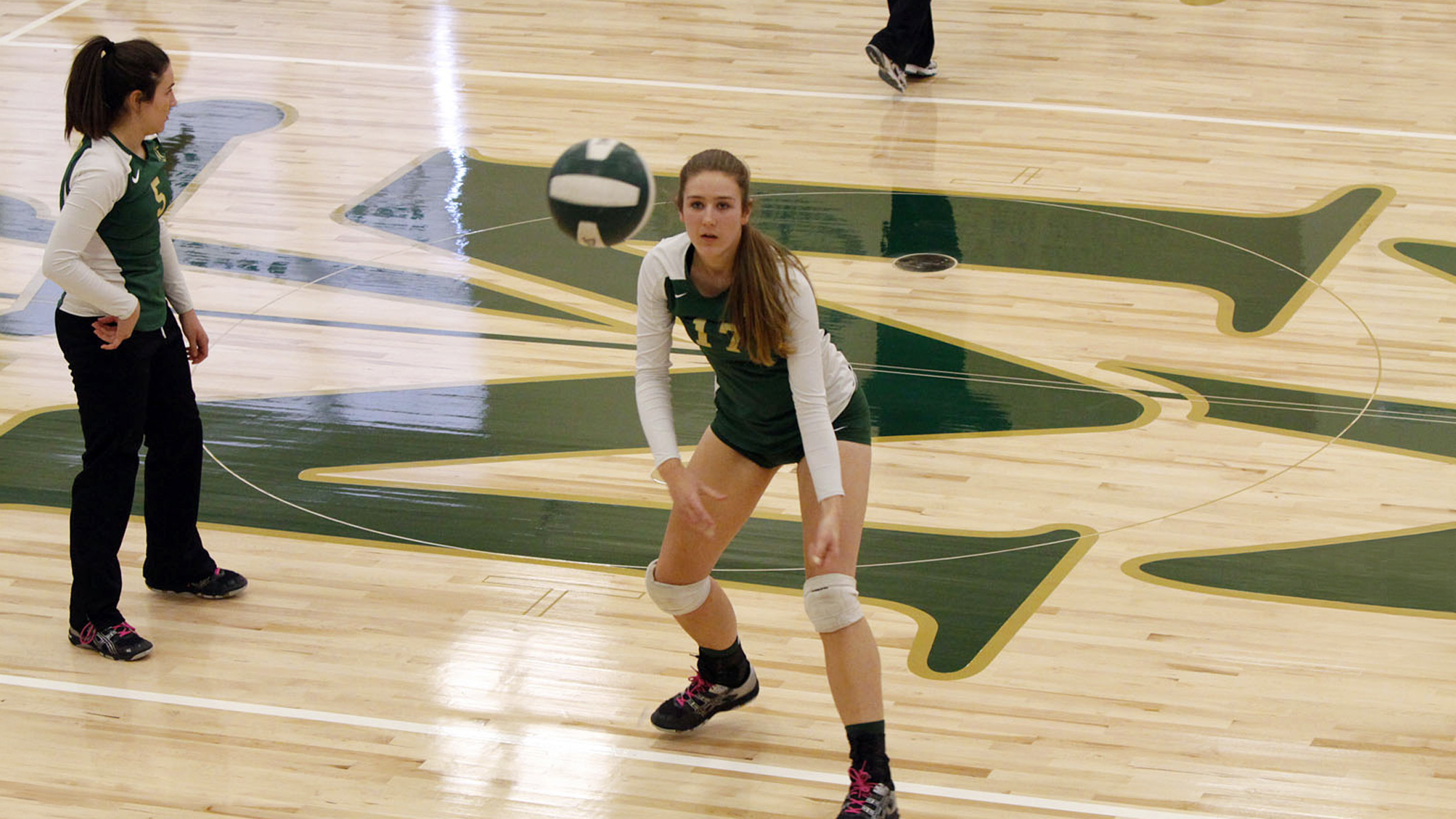 A student sets a volleyball in the Saint Monica Gymnasium, an educational architecture project.