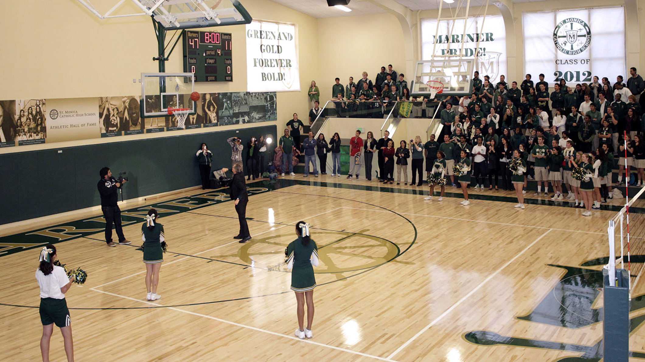 Students in the bleachers watch cheerleaders on the basketball court in the Saint Monica Gymnasium, an educational architecture project.