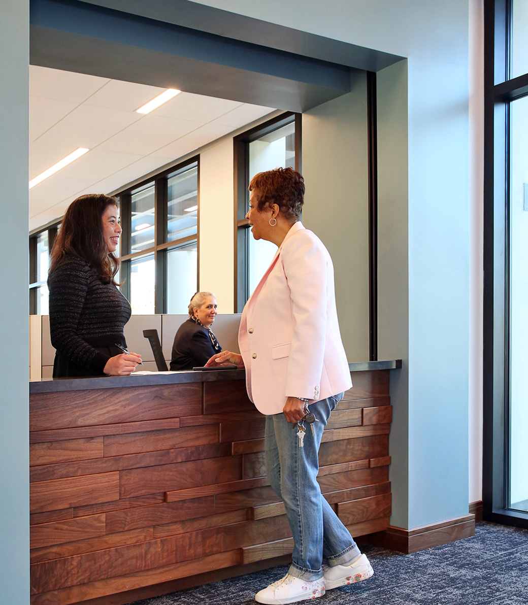 Two women talk over a reception counter at the Holy Family Church Parish Center in Glendale, a Pica+Sullivan Southern California religious architectural project.