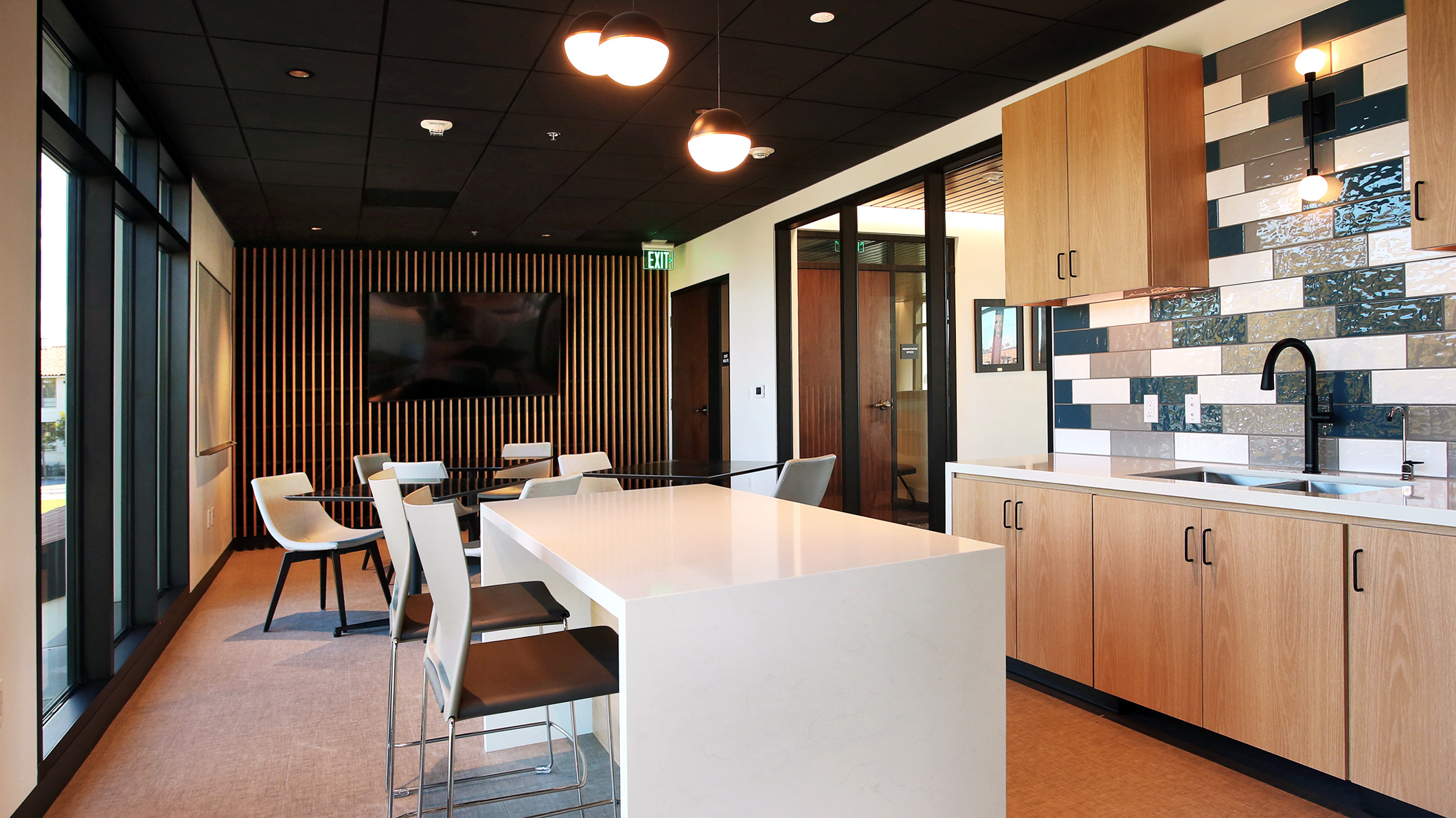 An empty kitchen and dining area with light pouring in from large windows in the Holy Family Church Parish Center in Glendale, a Pica+Sullivan Southern California religious architectural project.