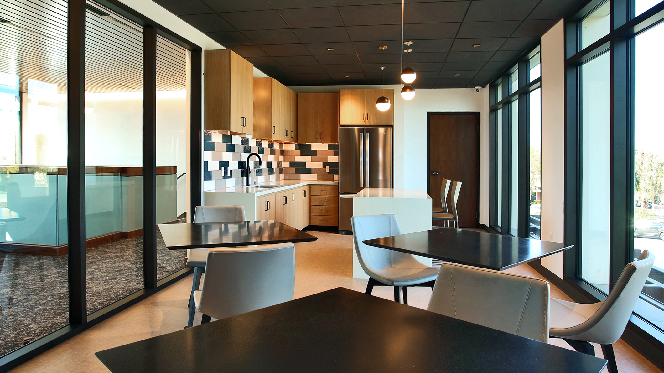 An empty kitchen and dining area with light pouring in from large windows in the Holy Family Church Parish Center in Glendale, a Pica+Sullivan Southern California religious architectural project.
