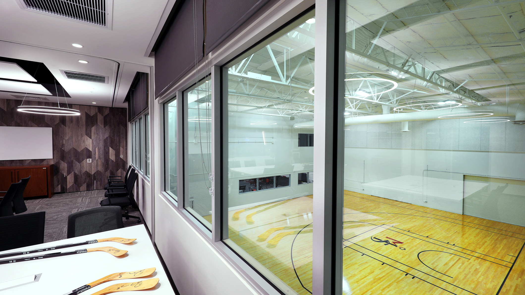 Room overlooking a basketball court through glass windows at the LA Kings Business Office in El Segundo, a Pica+Sullivan Southern California architectural project.