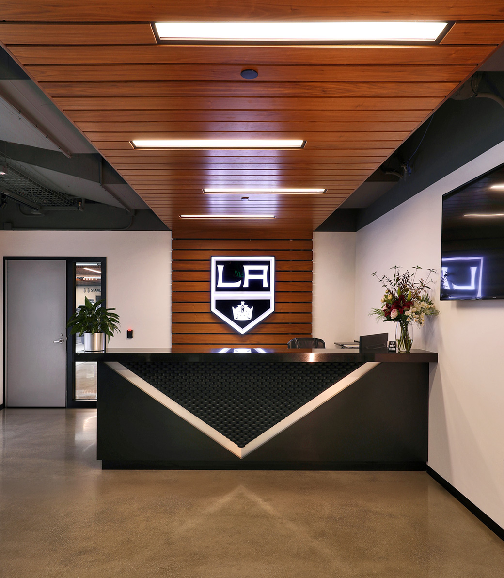 Reception desk with logo on the wall behind at the LA Kings Business Office in El Segundo, a Pica+Sullivan Southern California architectural project.