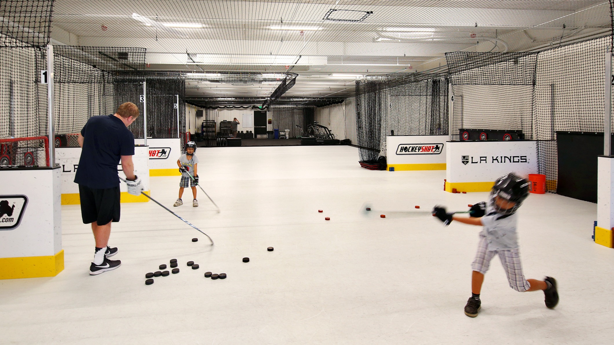 LA-KINGS-USC-011 A man coaches two young children in hockey in a practice area at the LA Kings USC Meyer Sports Rehabilitation Center in El Segundo, a Pica+Sullivan Southern California architectural renovation project.