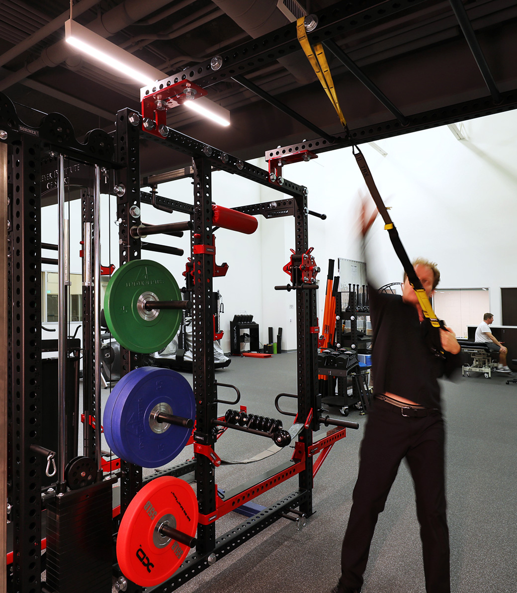 LA-KINGS-USC-017 A man exercises with a strap in a weight room and exercise area at the LA Kings USC Meyer Sports Rehabilitation Center in El Segundo, a Pica+Sullivan Southern California architectural renovation project.
