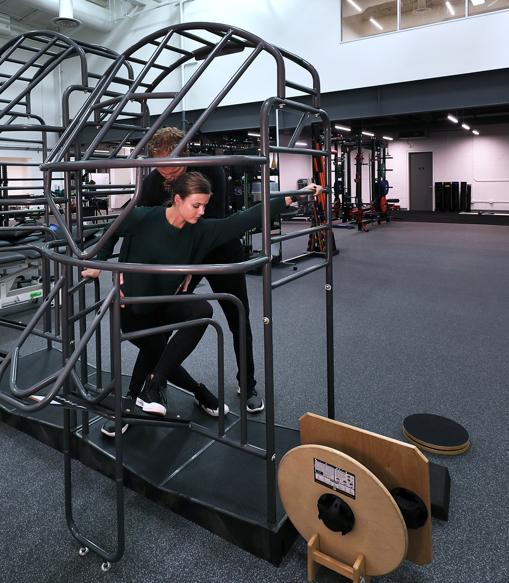 LA-KINGS-USC-018 A man helps a woman exercise in an exercise area at the LA Kings USC Meyer Sports Rehabilitation Center in El Segundo, a Pica+Sullivan Southern California architectural renovation project.