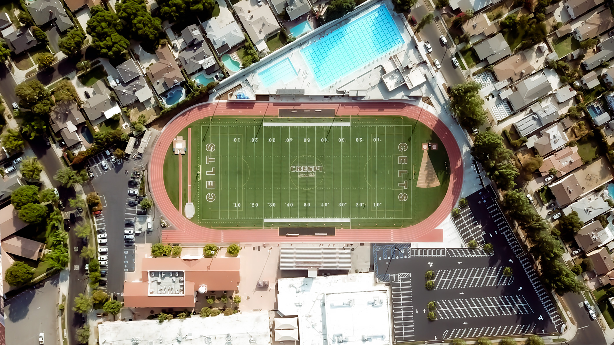 Sky view of the Robinson Family Aquatics Center at Crespi Carmelite High School in Encino, a Pica+Sullivan Southern California educational architectural project. The football field and racetrack are next to it.