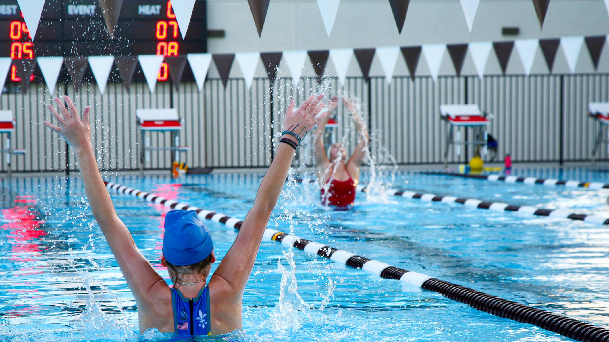 Two students emerge from the water in the pool at the Robinson Family Aquatics Center at Crespi Carmelite High School in Encino, a Pica+Sullivan Southern California educational architectural project.