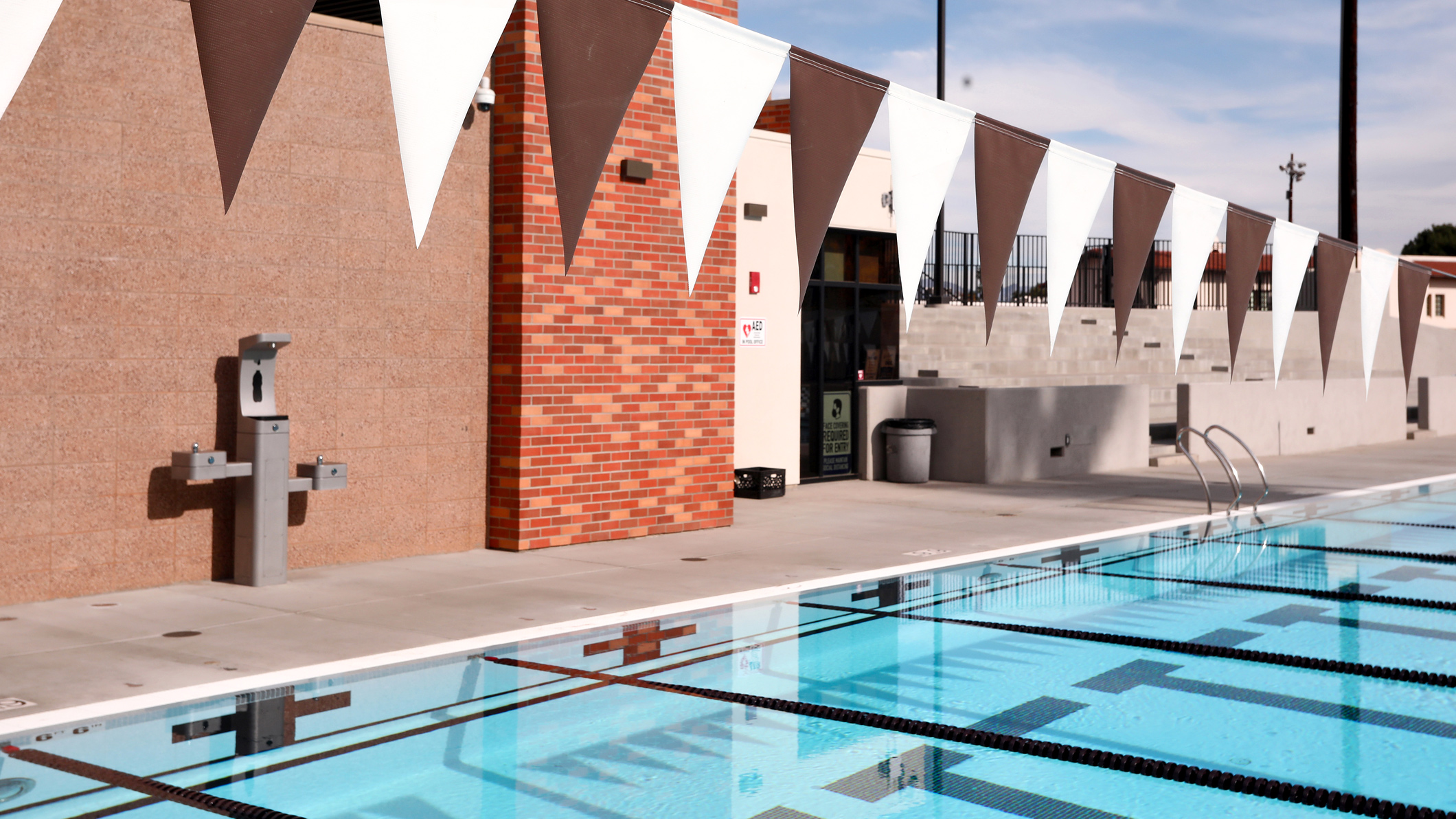 A pool set up for laps and racing at the Robinson Family Aquatics Center at Crespi Carmelite High School in Encino, a Pica+Sullivan Southern California educational architectural project. The bleachers are visible behind it.