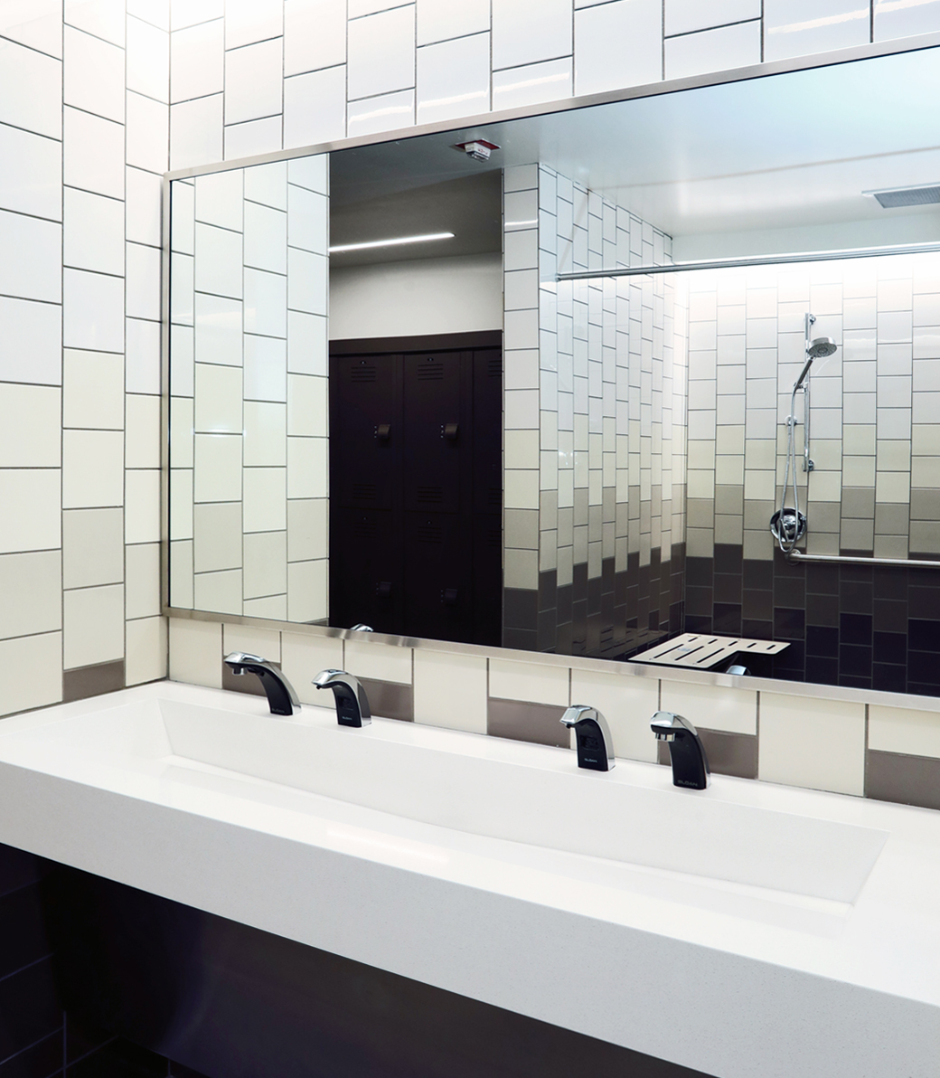 RFA-022 Sinks inside a changing room at the Robinson Family Aquatics Center at Crespi Carmelite High School in Encino, a Pica+Sullivan Southern California educational architectural project. Shower heads are visible reflected in the mirror.