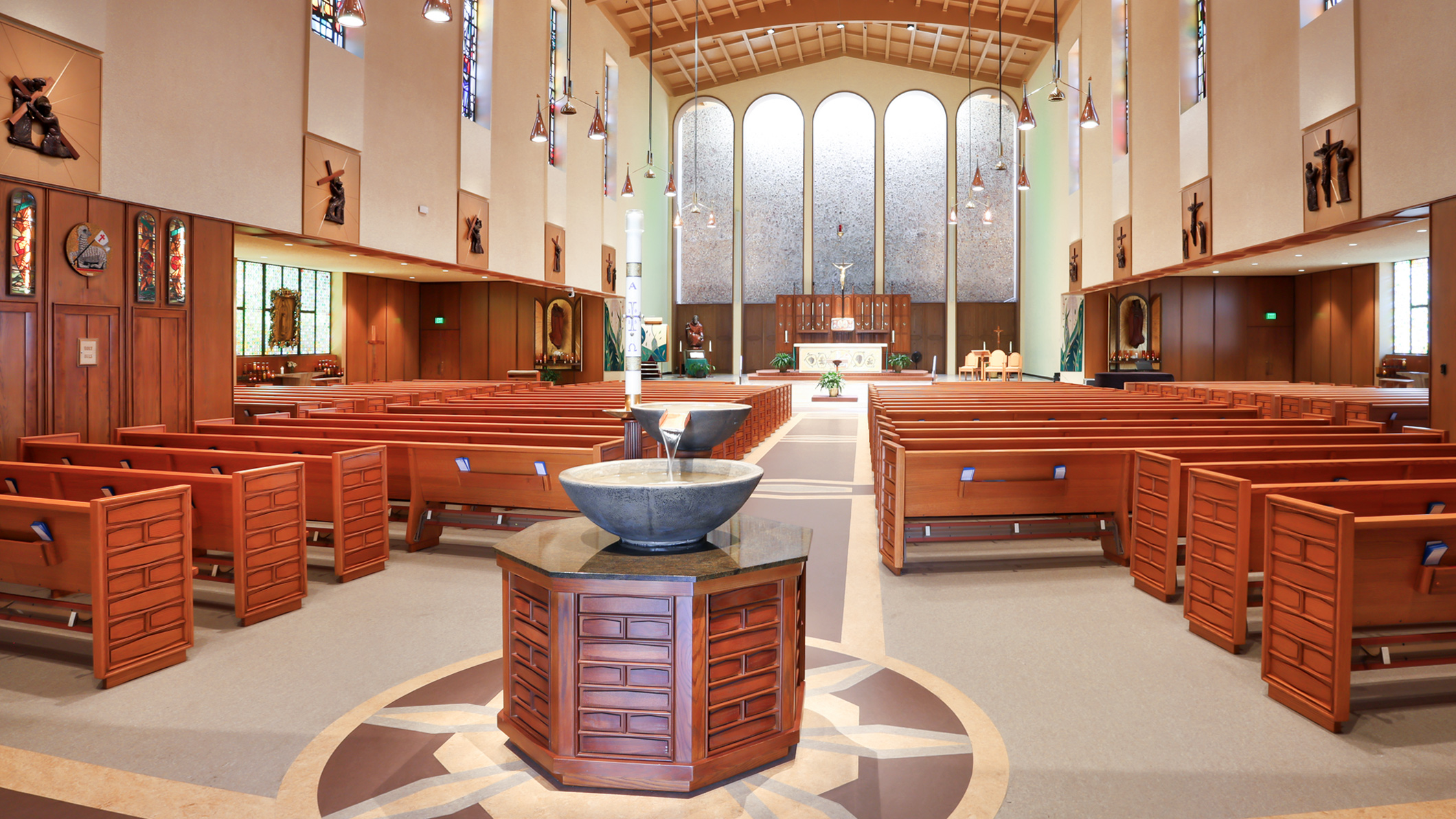 ST-PAUL_002 The baptismal font in front of rows of empty pews, leading up to the altar at Saint Paul the Apostle Church in Los Angeles, a Pica+Sullivan Southern California religious architectural renovation project.